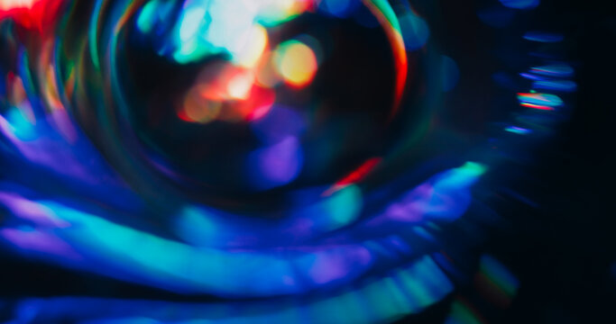 Light lens defocused. Holographic flare. Red green blue neon colorful luminosity on dark black background. Spectrum spin abstract optical effect.