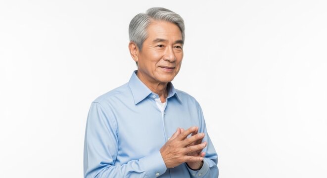 Elderly Asian man with grey hair wearing a light blue shirt smiling confidently against a white - Powered by Adobe