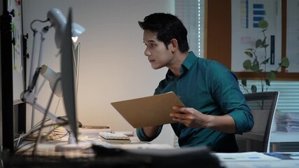 Focused asian businessman working overtime late at night in the office - Powered by Adobe