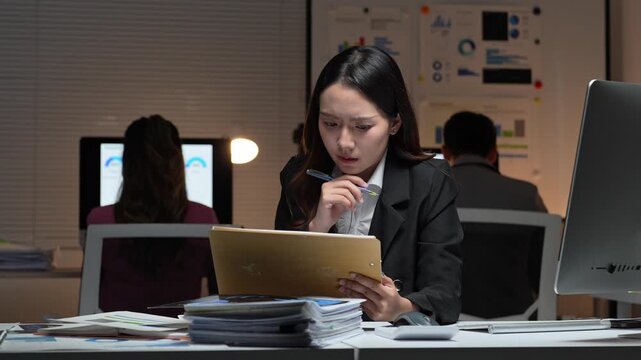 Stressed asian businesswoman working overtime in office at night