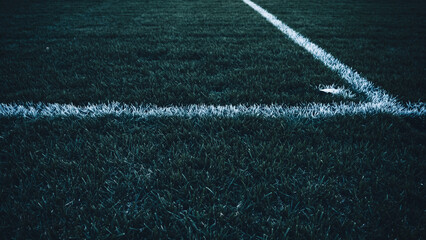 Obraz premium Close-up view of white lines on a dark green sports field, possibly artificial turf, showing a corner.