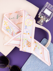 Close-up of a pink silk ribbon bow with a floral pattern   on purple table with women accessories