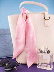 Close-up of a pink silk ribbon  with a cartoon bunny pattern on a  white leather bag