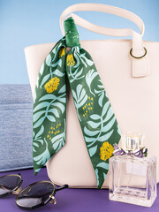 Close-up of a silk ribbon bow with a tropical leaf pattern on a white  leather bag