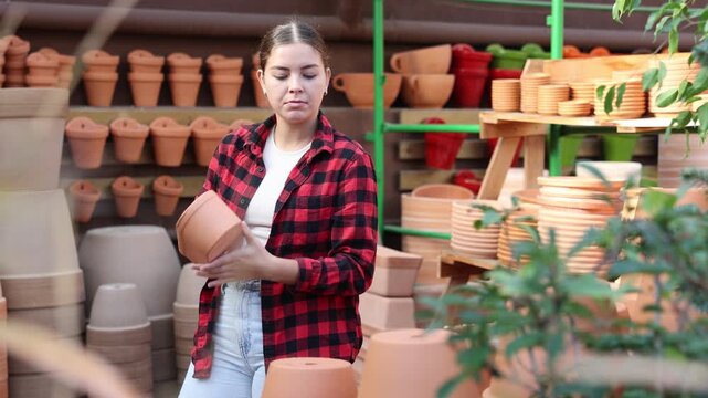 Portrait of woman choosing pots for flowers and trees in gardening market. High quality 4k footage - Powered by Adobe