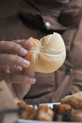 Hand holding a fresh bread roll during a cozy meal