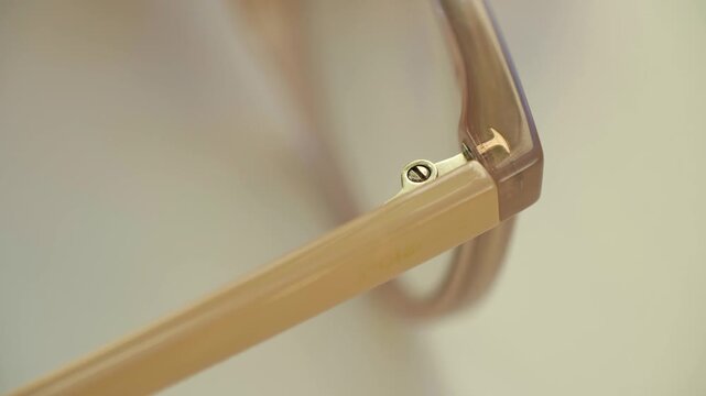 Extreme close up intricate detail of elegant eyeglasses hinge, temple, and frame, showcasing modern design, precision craftsmanship against clean, soft background. Detail of eyeglasses temple hinge