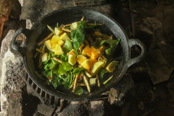 traditional cooking on an old stove. cooking vegetable soup in a black pan