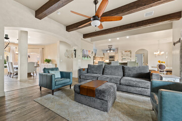 A spacious living room with a comfy couch, elegant chairs, and a ceiling fan