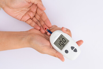 Woman's hands checking diabetes and hyperglycemia with digital blood sugar meter. Healthcare and...