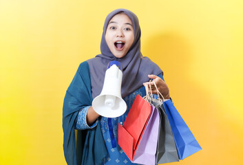 Excited woman in hijab with megaphone and shopping bags.