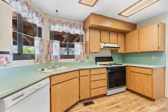 A kitchen with wooden cabinets, a stove, sink, and dishwasher