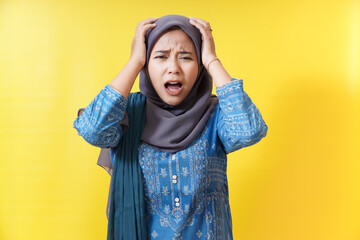 Stressed woman in hijab with hands on head.