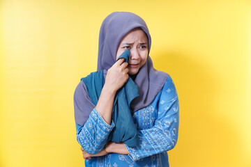 Sad woman in hijab wiping tears.