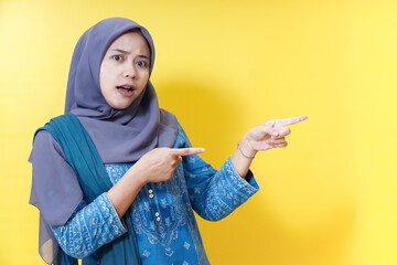 Surprised woman in hijab pointing to the side.