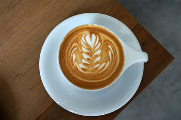 Close up white ceramic cup of hot Latte art coffee on wooden table