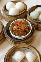 Noodle rolls and Braised Sichuan chicken feet served with Baozi in wooden basket, Steamed bun filled with various fillings mostly minced pork and sweet custard cream