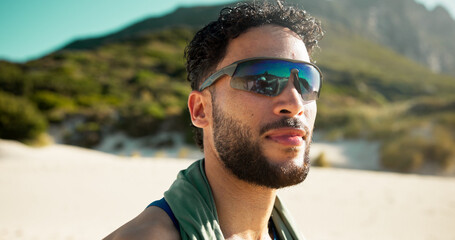 Hiking, sunglasses and thinking with man in nature for adventure hobby, planning or training. Fitness, shades and vision with hiker person outdoor on sand in mountains for exercise or wellness