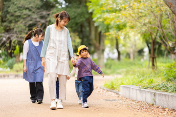 手を繋いで歩く保育士と園児