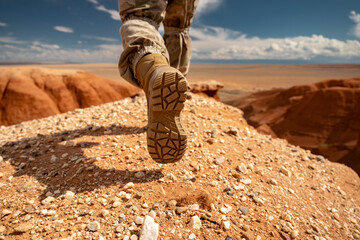 Close up photo of hikers leg while he is going at desert hill