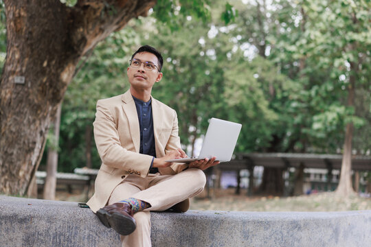 Man thinking while working remotely on laptop in park