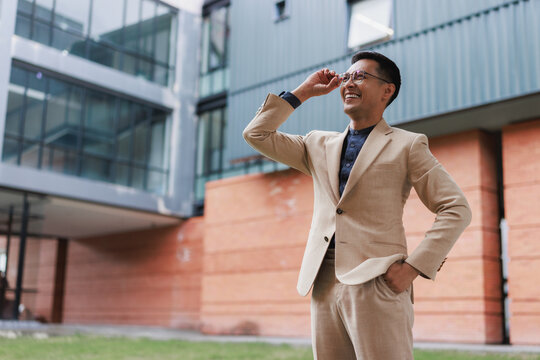 Confident Asian businessman smiling looking away in urban setting
