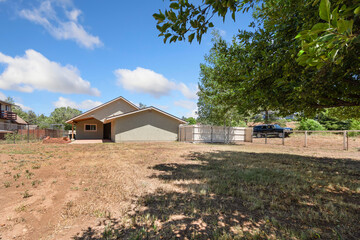 A quaint house in the middle of a vast field with a prominent tree