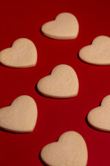 Fototapeta premium Scattered heart-shaped vanilla cookies on a bold red background, conveying romance, affection, and Valentine’s Day celebration