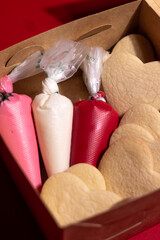 Heart-shaped vanilla cookies in a kraft box with red, pink, and white icing bags, perfect for Valentine’s Day decorating kits and DIY baking