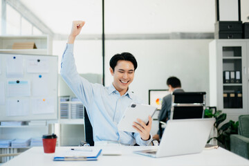 Asian businessman are delighted and happy with the work they do on their tablet, laptop and taking notes at the office.