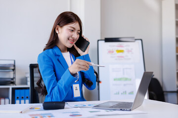 Young businesswoman discussing work on smartphone in office