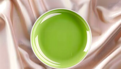 Green ceramic plate on soft pink satin fabric background
