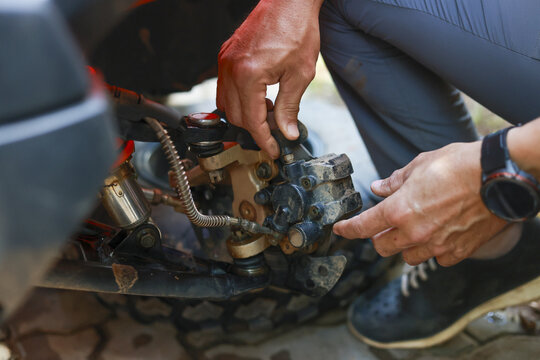 Focused mechanic hand doing repair work on vehicle engine. This closeup shows fixing and maintenance service for complex automotive part, expressing concentration