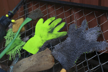 Messy collection of dirty car washing equipment. green rubber glove, grey wash mitt, brush, and...