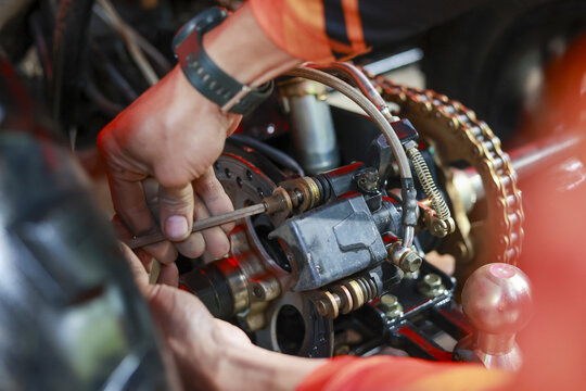 Professional mechanic showing intense concentration while performing repair on machine part. This technician uses screwdriver for precise maintenance on brake system