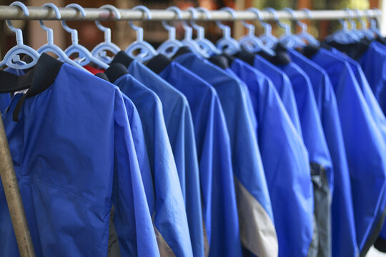 Many blue workwear uniform shirt hanging in neat row on clothing rack. orderly arrangement of apparel represents clean, organized laundry or retail shop for service