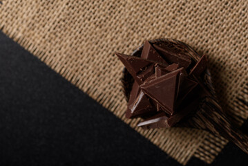 Small pieces of chocolate bars are arranged on a black background
