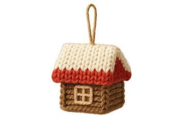 A charming knitted log cabin ornament with a red and white snowy roof is a rustic handmade decoration for a cozy winter holiday celebration, crafted from soft yarn