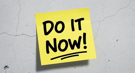 Yellow sticky note with Do It Now message on a textured with white wall.