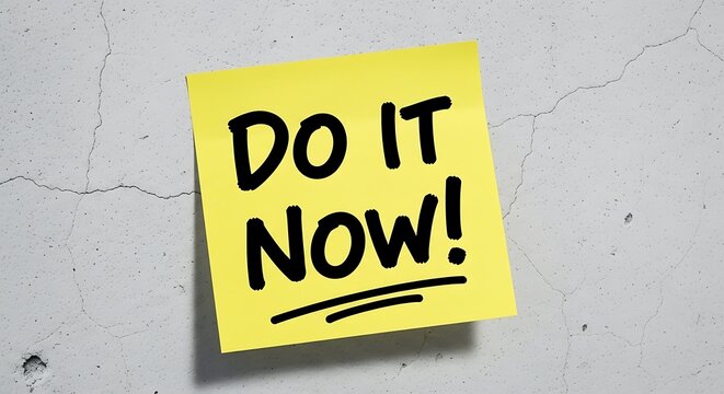 Yellow sticky note with Do It Now message on a textured with white wall.
