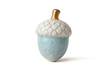 A decorative ceramic acorn figurine with a speckled blue nut, textured white cap, and a shiny gold stem, representing an elegant piece of autumn home decor