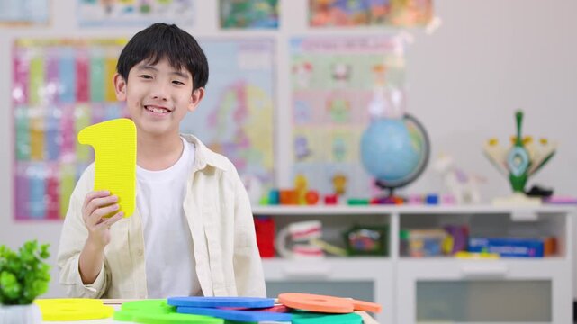 Smiling Child Holding Foam Number One in Classroom