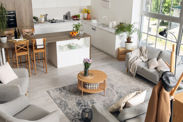 Interior of light open plan kitchen with coffee table, armchairs and sofas