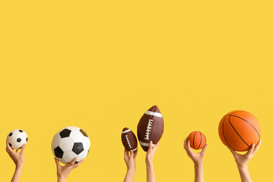 Female hands with sports balls on yellow background
