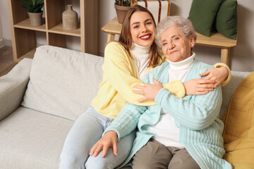 Young woman hugging her grandmother on sofa at home
