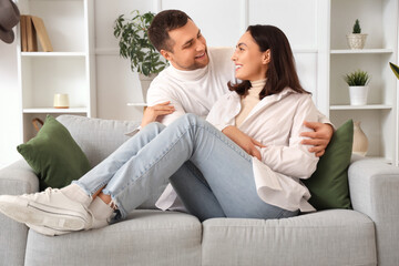 Happy young couple hugging on sofa at home