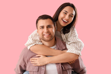 Fototapeta premium Happy young couple hugging on pink background