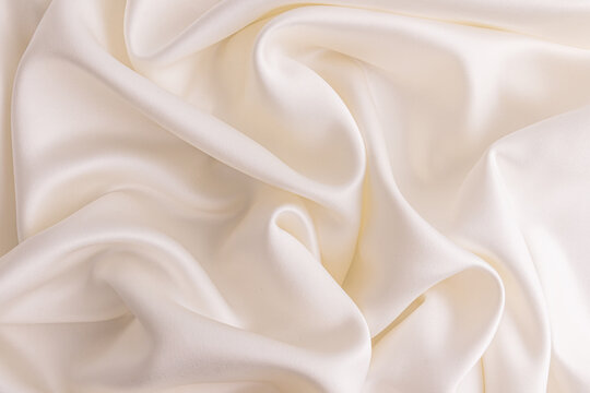 Luxurious wedding background in beige satin fabric. delicate waves of creamy satin fabric. layout for design. Beautiful wavy fabric surface.