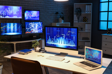 Naklejka premium Computer and laptop with stock data on trader's desk in dark office at night