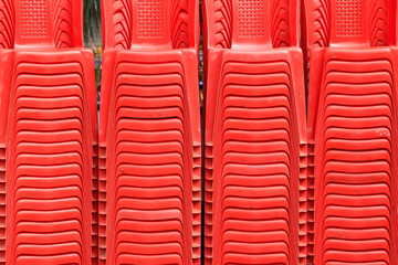 Fototapeta premium Close up view of many stacked red plastic chairs, abstract background.